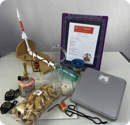 An ABC Science lesson kit: bottle rocket, scales, tongs, lesson plan and materials laid out ready for class